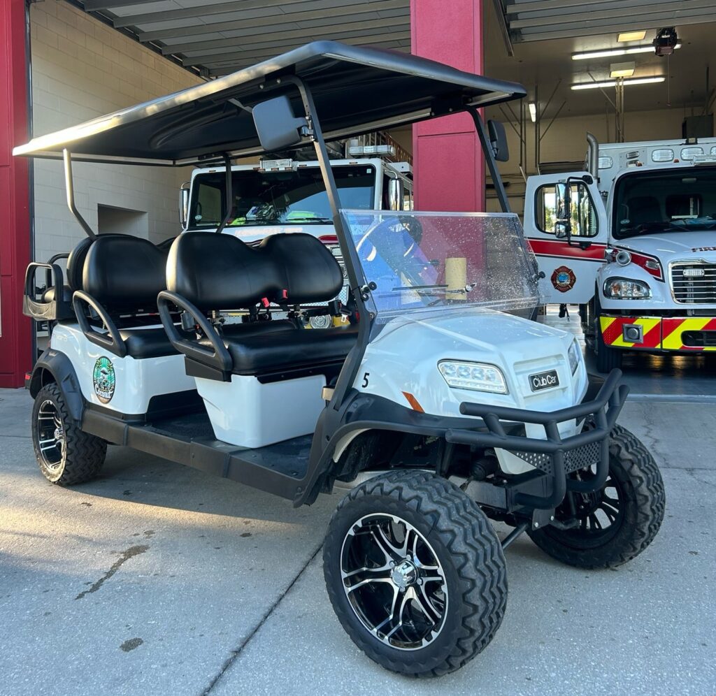 Anna Maia Island golf cart rental parked next to firetruck. Coconut Rentals is owned and operated by first responders