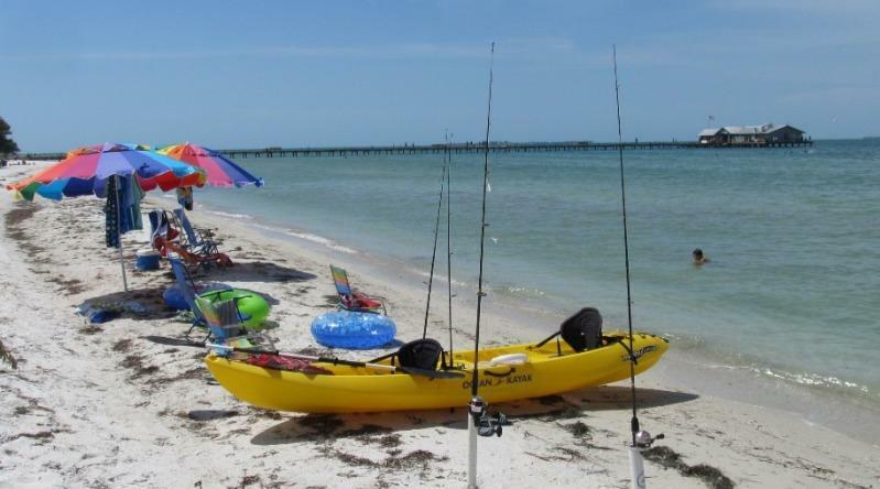 A sun-dappled scene of a tranquil inshore fishing spot on Anna Maria Island. In the foreground, a shallow, meandering creek cuts through lush mangrove forests, its glassy surface reflecting the vibrant hues of the surrounding vegetation. Schools of silvery baitfish dart through the crystal-clear waters, luring in predatory game fish. In the middle ground, a lone angler casts their line, patiently waiting for a strike. The background features the island's iconic white-sand beaches, swaying palm trees, and a distant, hazy horizon, bathed in the warm glow of the afternoon sun. The overall mood is one of serene, idyllic tranquility, inviting the viewer to imagine the thrill of an inshore fishing adventure on this picturesque island.